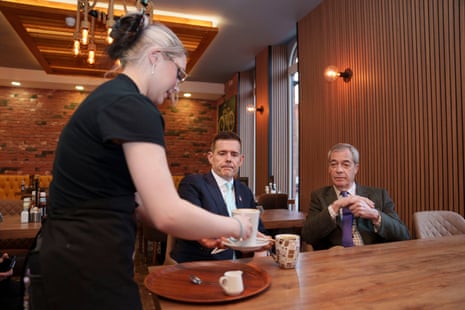 Farage and Goodwin sat in a cafe as a worker serves them tea
