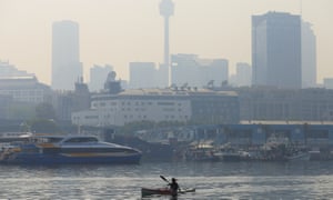 A paddler is seen as smoke haze drifts over the CBD in Sydney