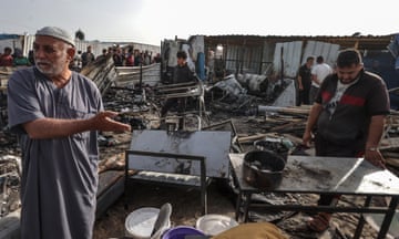 Palestinians observe the destruction caused by an Israeli army airstrike on tents of displaced Palestinians living near the United Nations Relief and Works Agency for Palestine Refugees (UNRWA) warehouses in Rafah, Gaza