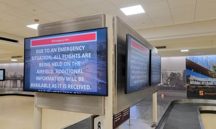An information screen in Reagan National Airport’s empty baggage claim area displays emergency instructions.