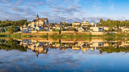 A river with an old town on the far shore reflected in the water