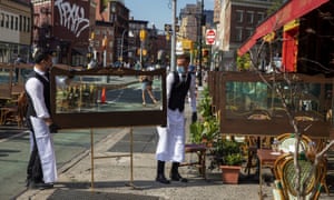 Waiters at a restaurant adjust social distancing screens outside for outdoor seating seating that follows current health guidelines to slow the spread of Coronavirus (COVID-19) at a restaurant in New York City on June 25th.