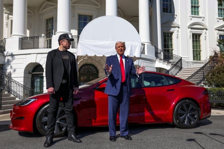 Elon Musk and Donald Trump standing in front of a red electric car parked in front of the president’s official home