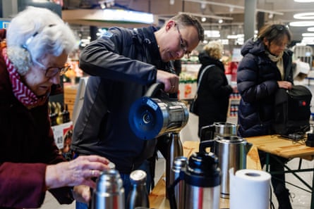 People pouring free tea or coffee at a supermarket.