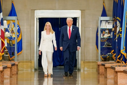 a woman and a man walk along a corridor