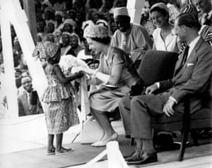 1961: Elizabeth receives a bouquet from a young girl, watched by the Duke of Edinburgh and others, during the royal tour of Sierra Leone