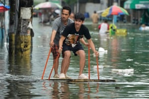 Men use poles to ride an improvised float along a flooded road
