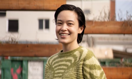 Sabrina Imbler, with shoulder-length hair, smiling in front of a building