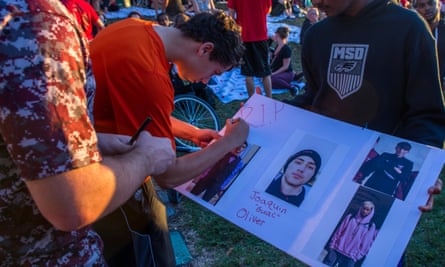 Students sign a poster with photos of Joaquin Oliver