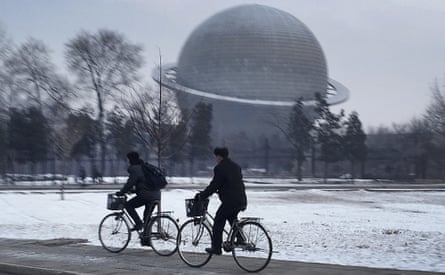 North Koreans cycle past a planetarium at the Three Revolutions Exhibition Hall in Pyongyang.