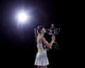 Elena Rybakina kisses the trophy with backlight behind her