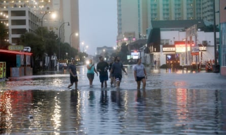 People walk up a flooded Ocean Boulevard in North Myrtle Beach.
