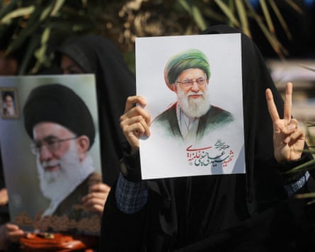 Mourners hold up pictures of Ali Khamenei.