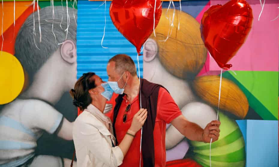 A couple kiss wearing masks at an art exhibition to thank medical staff at Pitié-Salpêtrière hospital in Paris.