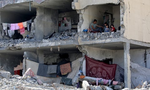People sit among the ruins of a destroyed building in Gaza