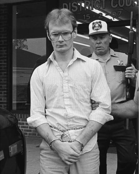 Yarris in handcuffs being led away by a police officer.