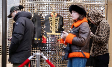 A military-style jacket in the window as people queue past.