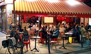 People enjoy a drink in a cafe terrace as French President Emmanuel Macron deploys curfew amid accelerating coronavirus pandemic.