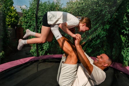 A man and a nine-year-old girl playing together on a trampoline in a garden