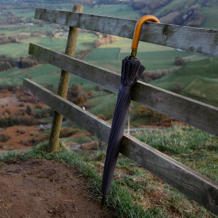 Long umbrella hooked on top of a three-rail fence