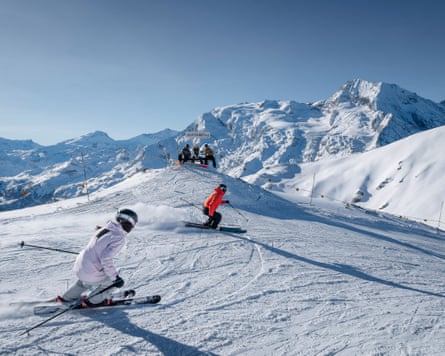 Two teenagers skiing down a piste on sunny day