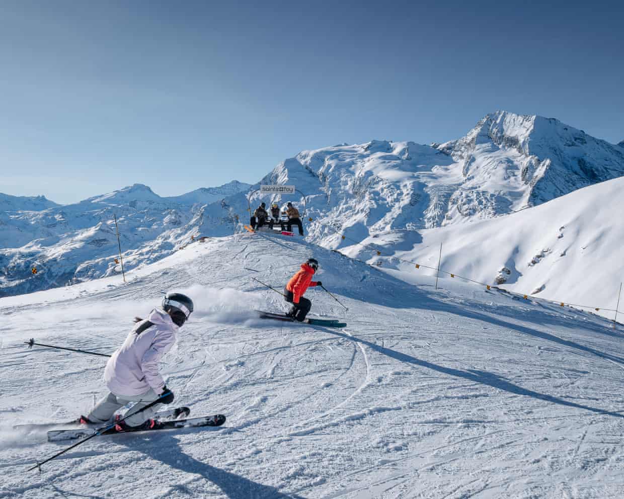 Two teenagers skiing down a piste on sunny day