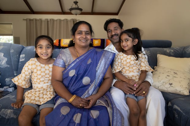 Priya and Nades Nadesalingam are sitting on their couch in their home with their daughters Tharnicaa and Kopika