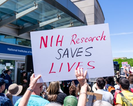 a person holds a sign that says 'NIH research saves lives'