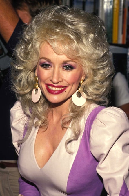 A woman smiling while wearing a pale pink and purple top with puffy shoulder sleeves