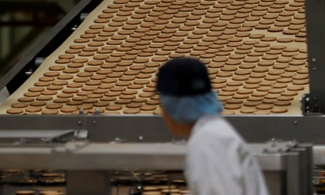 Worker in front of conveyer belt of biscuits.