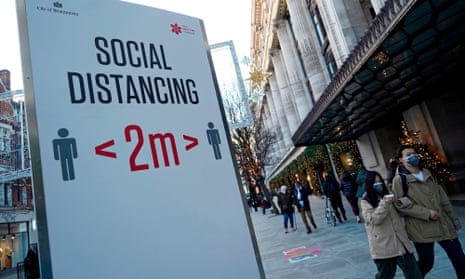 People walk past a sign asking people to social distance on Oxford Street in central London.
