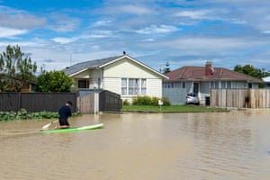 A man paddles through flood waters around homes in Napier