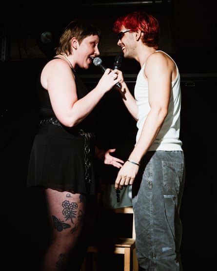 Ashley Blair and Drew Reilly face each other with a microphone
