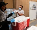 A person standing by a cooler hands another person a styrofoam meal container and a bottle of water