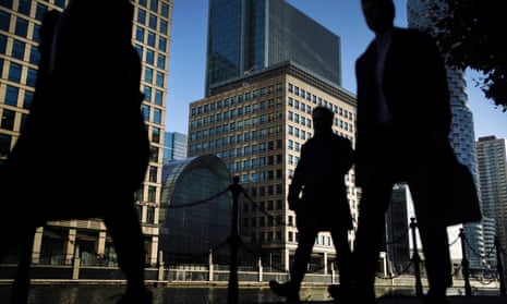 silhouetted commuters pass tall offices in london