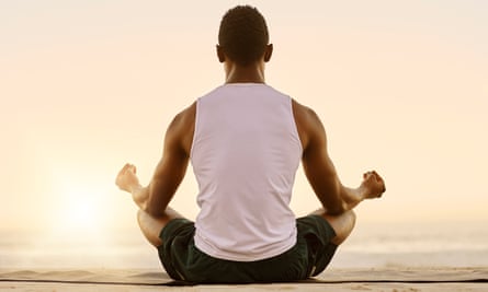 A man on a beach doing breath exercises and meditation