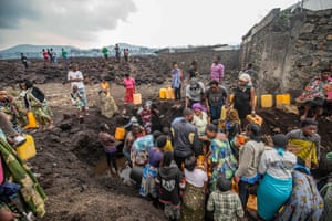 People gather at a water point in a lava-covered field in Goma