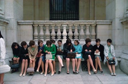 Group of women sat on a bench outside a historic building in Paris.