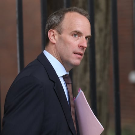 A man with short hair, wearing a blue suit, and holding a batch of pink papers.