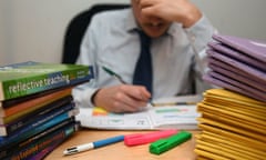 Image of a school teacher looking stressed next to piles of classroom books.