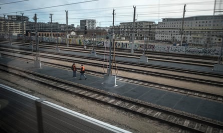 View from out of a train window, of railway tracks and apartment blocks behind