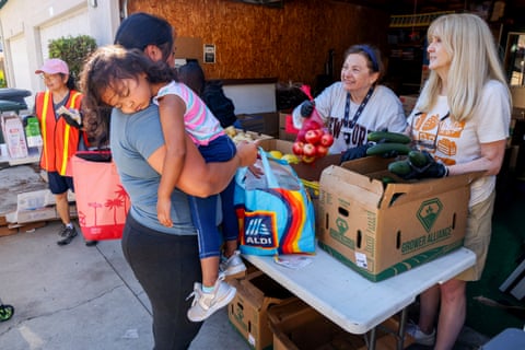 a mother holds her child as she receives food at a food bank