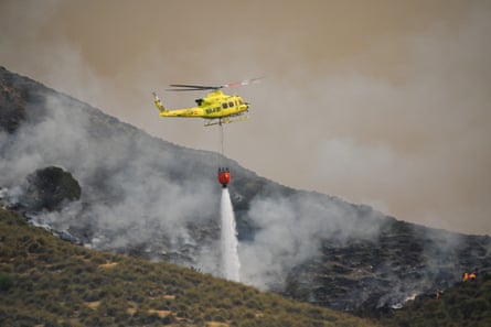 A fire service helicopter drops water onto one of the hotspots of the wildfire.