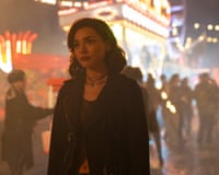 Paulina Chávez, in a leather jacket, stands amid blurred, glowing carnival lights at night