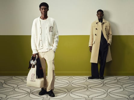 One man in a long beige duffel coat and another in a white cardigan and beige trousers