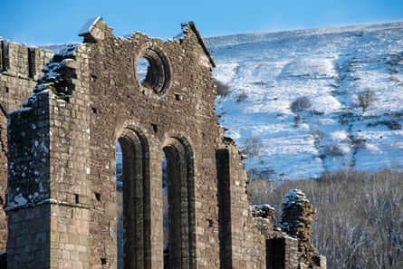 facade of old priory ruin with snowy hillside in background