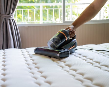 Cropped view of man removing dust on mattress with vacuum cleaner
