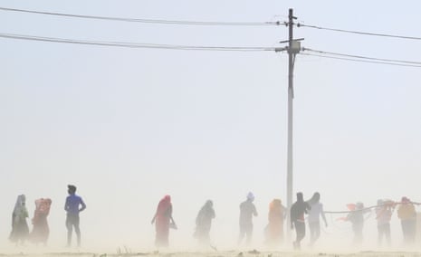 People walk through a dust storm on a hot day in Uttar Pradesh, India.