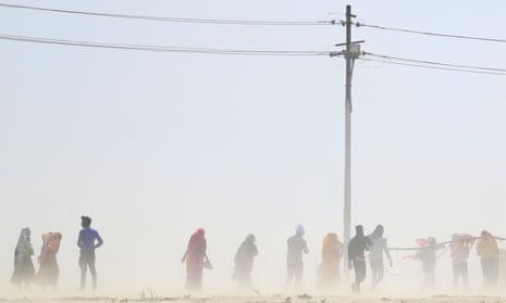 People walk through a dust storm in Prayagraj, India.