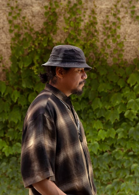 Man in bucket hat and plaid shirt stands sideways